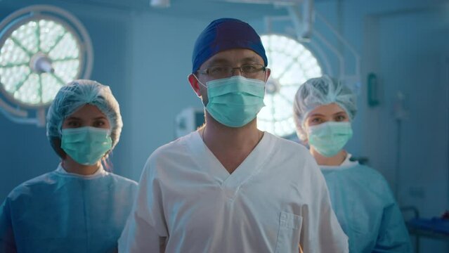 At the hospital in the operation room medical team before start the surgery posing in front of the camera they are full equipment wearing protective masks and medical uniform
