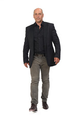 front view of a man with blazer and jeans walking and serious  looking at camera on white background,