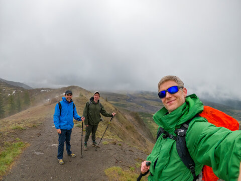 Adventurous Athletic Male Hikers Standing On A Trail Facing The Camera Smiling In Early Spring On A Cloudy Day In The Pacific Northwest.