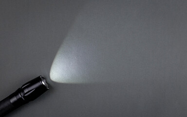 A bright beam of light from a flashlight shines on a gray background