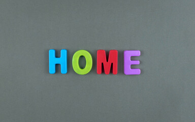 The word home is laid out of multicolored letters on a grey texture background. Concept