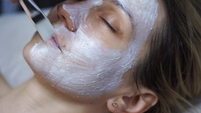 woman on reception at the doctor-beautician. To the beautiful girl put the rejuvenating mask on a face