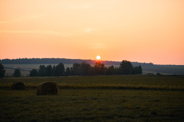 Field with haystacks at sunset. Harvest concept