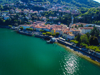 Fototapeta na wymiar Aerial view of Lake Como. city ​​center. A local ferry arrives in the city. Bell tower. Tourism and romance. Mountains around the lake. Red roofs. Green Planet. Sailing yacht. Italy, Bellano, 10.2022