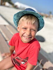 boy in rad shirt and hat, smiling, happy playing in a park