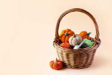 Knitted orange green and beige pumpkins in a basket on a orange background, knitting hobby, autumn composition. Halloween concept.