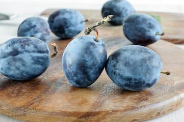 Dark blue plums close-up on a wooden background. Selective focus in natural light