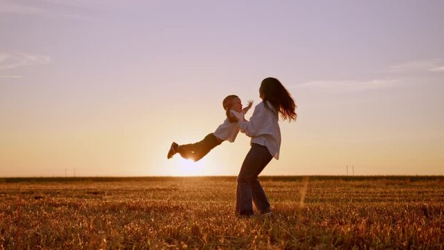 Happy mom catching son running to her and spinning around with him at sunset.