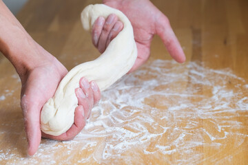 Hands of man stretches dough during cooking and making pizza