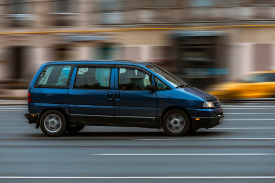 side view rolling shot of old MPV car in motion. Citroen Jumpy driving along the street in city with blurred background