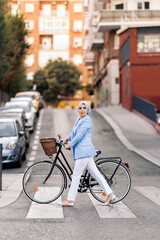 Muslim woman walking with her bicycle crossing the street looking to a side