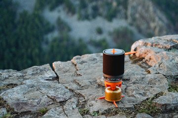 Tourist utensils bowler standing on the edge of a rock rock, camping gas for cooking on a hike,...