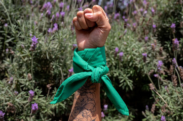 Mano de mujer feminista con tatuajes y pañuelo verde en la calle. - obrazy, fototapety, plakaty