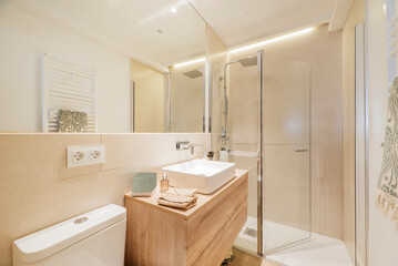 Fototapeta na wymiar Bathroom with wooden vanity with frameless mirror