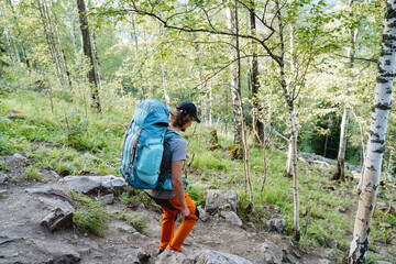 The sight of a man descending from the mountain, a guy goes hiking with a backpack, down the trail,...