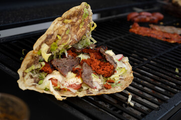 top view of Mexican food Tlayuda de cecina y chorizo and its preparation ingredients on a wooden table, frijoles, beans, cecina, sausage, lettuce, sauce, fruit water