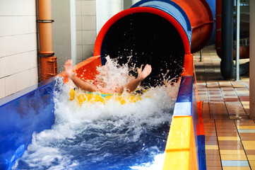 People have fun in the water park. A person's feet slide down a slide under water.