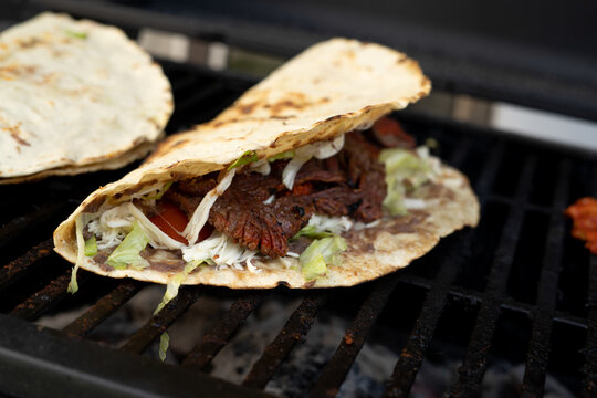 top view of Mexican food Tlayuda de cecina y chorizo and its preparation ingredients on a wooden table, frijoles, beans, cecina, sausage, lettuce, sauce, fruit water - Powered by Adobe