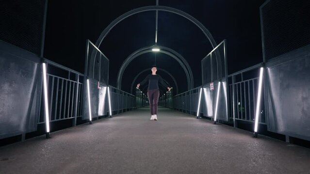 woman dancer is moving like robot or doll in dark tunnel with led lights, flashmob of modern dancers