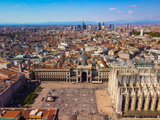 Aerial view of Piazza Duomo in front of the Gothic cathedral in the center. Drone view of the gallery and rooftops during the day. Flight over the city. People in the city. Milan. Italy 2022