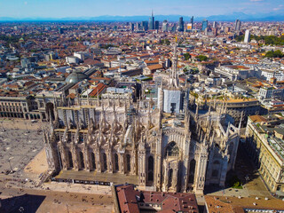 Aerial view of Piazza Duomo in front of the Gothic cathedral in the center. Drone view of the gallery and rooftops during the day. Flight over the city. People in the city. Milan. Italy 2022