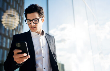 A male entrepreneur in a business suit uses a phone chat with a colleague.