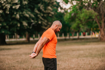 Happy positive sportsman during outdoor workout, man wearing sports outfit warming up muscles,enjoying active lifestyle outside in park