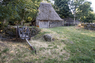 grange ancienne avec toit de chaume et muret en pierres en Haute Loire en été