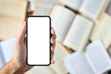 Smartphone with a blank white display in hand against the background of open books..