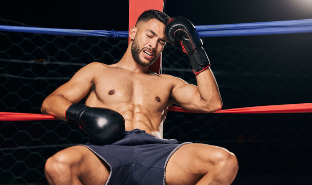 Sports, boxing ring and tired frustrated boxer with head pain, injury or fatigue from exhibition competition. Defeat or failure in fight challenge, workout or training burnout from fitness exercise