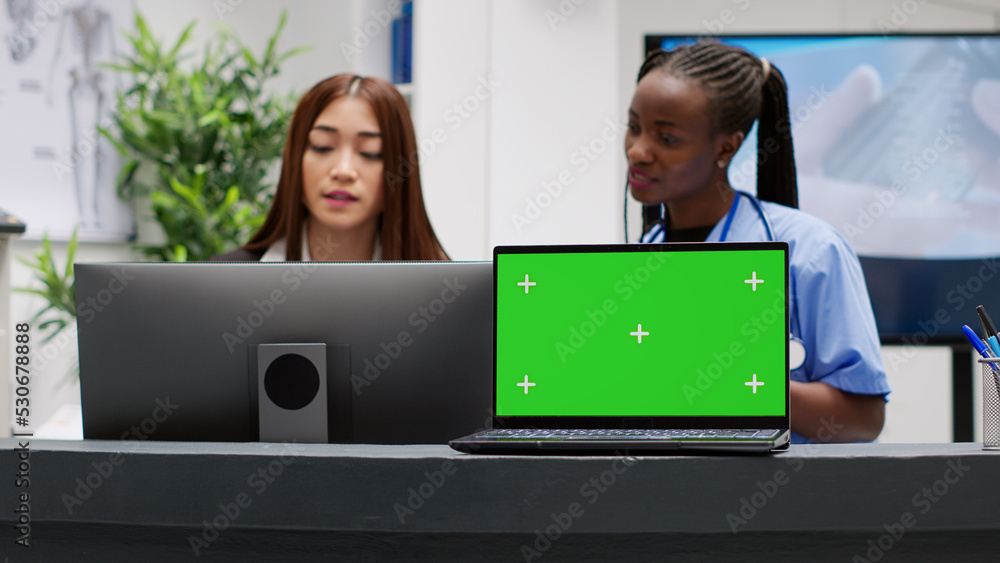 Poster diverse receptionist and nurse working with greenscreen on laptop at reception counter desk. isolate