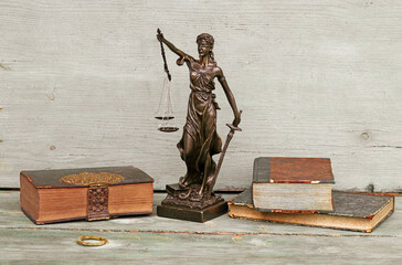 Justitia Figur und alte Bücher auf einem Holzuntergrund. Gerechtigkeit, Waage und Gericht

