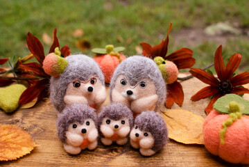 Felted grandfather and grandmother hedgehogs near their grandchildren small hedgehogs made also of wool on a wooden background with autumn decor