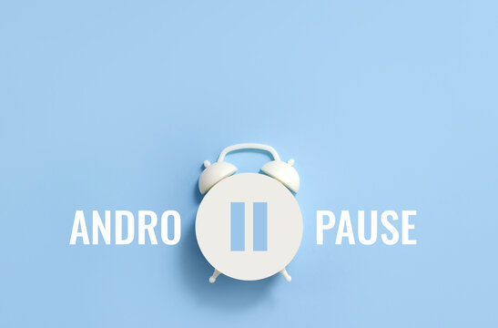 Word Andropause, pause sign on a white alarm clock on blue background. Minimal creative concept age-related androgen deficiency. Selective focus, copy space