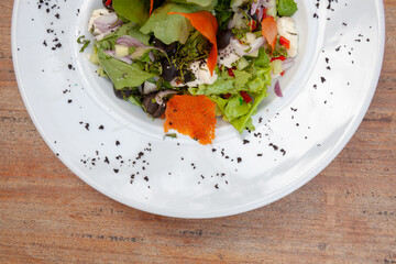 salads on a white plate with a light wood background
