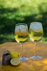 glasses with lemon cocktail and slices inside next to lemons and grater