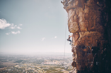 Mountain, rock climbing and sport with a sports woman and climber abseiling on a mountainside...