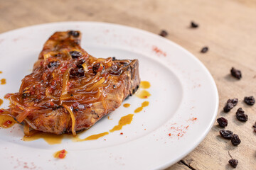 Different cuts of meat, chicken and pork on a white plate on a light wooden background
