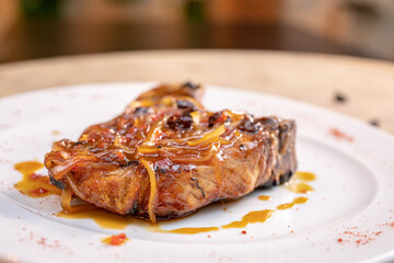 Different cuts of meat, chicken and pork on a white plate on a light wooden background
