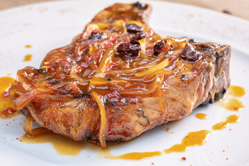 Different cuts of meat, chicken and pork on a white plate on a light wooden background
