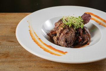 Different cuts of meat, chicken and pork on a white plate on a light wooden background
