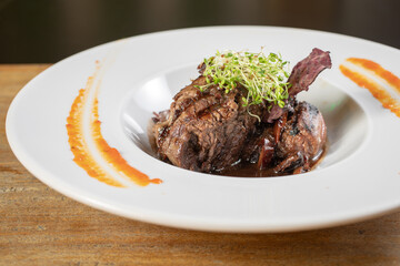 Different cuts of meat, chicken and pork on a white plate on a light wooden background

