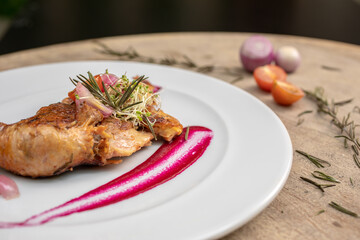 Different cuts of meat, chicken and pork on a white plate on a light wooden background
