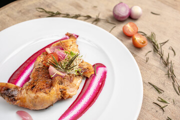 Different cuts of meat, chicken and pork on a white plate on a light wooden background
