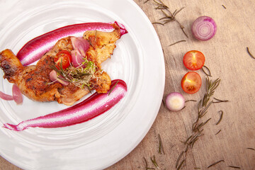 Different cuts of meat, chicken and pork on a white plate on a light wooden background
