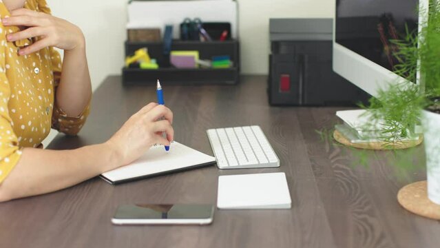 female hands work desk computer talking phone holding pen nocking table listen carefully thinking. unrecognizable woman have phone talk business negotiation sit at home office, white keyboard touchpad