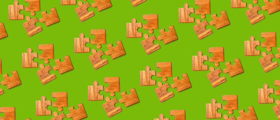 Wooden pieces of jigsaw puzzle on green background. Pattern for design