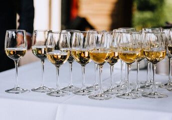 A lot, a row of glass glasses with champagne stands on the table. Photography, party.
