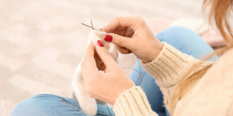 Young woman knitting warm mittens at home, closeup