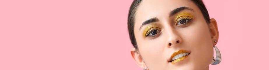 Attractive young woman with shiny golden makeup on pink background with space for text